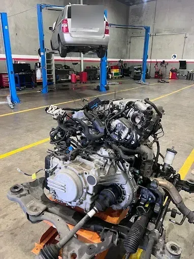 Engine and transmission assembly removed and placed on the workshop floor between vehicle hoists